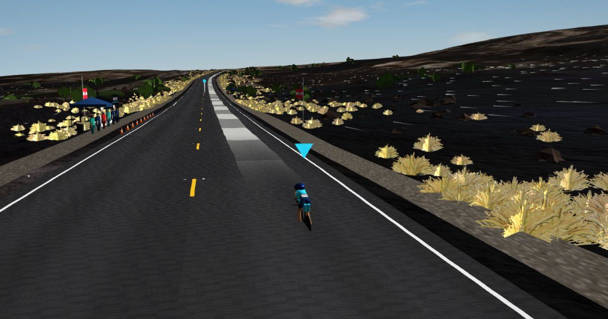 Chase view of a rider on the Queen K with fountain grass and lava beside the road.